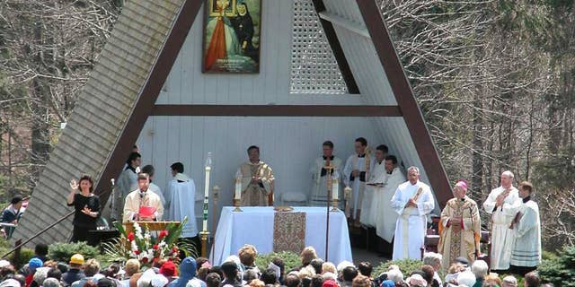 FILE- In this April 27, 2003, file photo, people attend the Mass officiated by Bishop Thomas L. Dupre, third from right, at the National Shrine of The Divine Mercy in Stockbridge, Mass. Dupre, the first Roman Catholic bishop in the United States to be indicted on a sexual-abuse claim during a flood of abuse accusations against church officials, died Friday, Dec. 30, 2016, according to the Diocese of Springfield. Dupre was 83. (AP Photo/Alan Solomon, File)