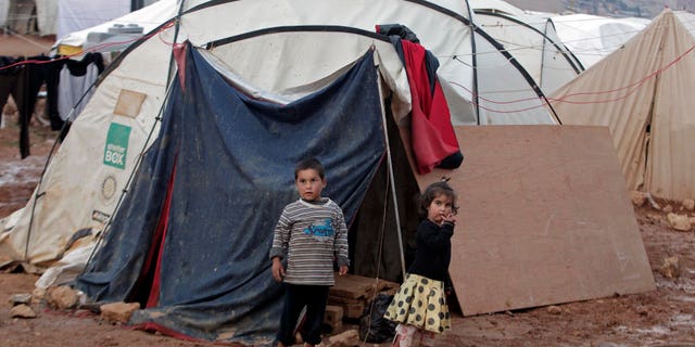 CAPTION CORRECTION, CORRECTS SPELLING OF TOWN - Syrian children stand near their tent at a refugee camp in the eastern Lebanese border town of Arsal, Lebanon, Monday, Nov. 18, 2013. Thousands of Syrians have fled to Lebanon over the past days as government forces attack the western town of Qara near the border with Lebanon. (AP Photo/Bilal Hussein)