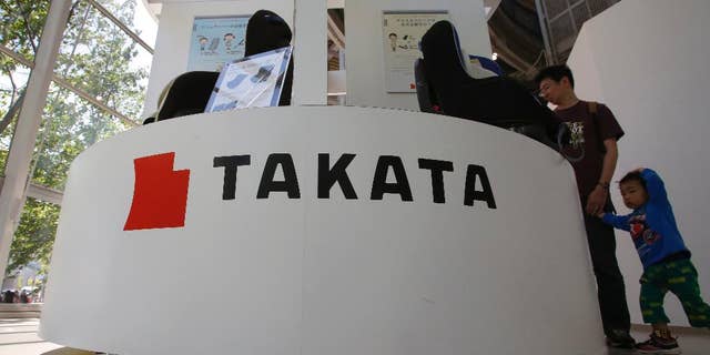 In this Wednesday, May 4, 2016 photo, visitors look at child seats manufactured by Takata Corp. at an automaker's showroom in Tokyo. Takata, the Japanese auto-parts maker behind a massive air-bag recall, is expecting a return to profit for the fiscal year through March 2017, although it just agreed to do more recalls. Tokyo-based Takata reported a 13 billion yen ($120 million) loss Wednesday, May 11, for the fiscal year ended March — the second straight year of red ink. (AP Photo/Shizuo Kambayashi)