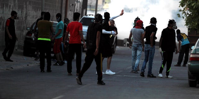 Bahraini youths carrying petrol bombs and stones confront riot police firing tear gas, stun grenades and shotguns after the funeral for Hussain Mahdi Habib, 20, in Sitra, Bahrain, on Sunday, Oct. 20, 2013. Habib, who was wanted by authorities for escaping from prison, received a 15-year sentence in absentia for his participation in the pro-democracy uprising, and was found beaten and shot dead. (AP Photo/Hasan Jamali)