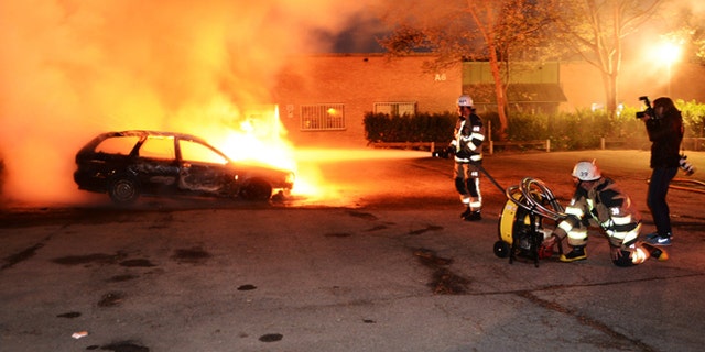 May 21, 2013: Firemen extinguish a burning car in the Stockholm suburb of Kista after youths rioted in several different suburbs around Stockholm for a third consecutive night.