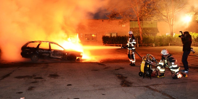 May 21, 2013: Firemen extinguish a burning car in the Stockholm suburb of Kista after youths rioted in several different suburbs around Stockholm for a third consecutive night.