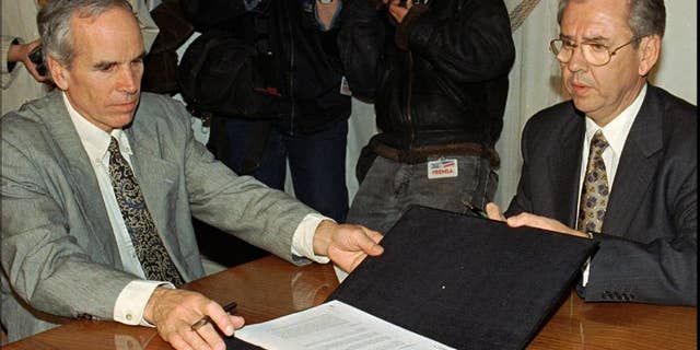 FILE - In this July 7, 1997, file photo, American millionaire Douglas Tompkins, left, and Juan Villarzu, chief of staff of the Chilean president, hold the text of an accord signed in Santiago, Chile. Officials in Chile said Tuesday, Dec. 8, 2015, that the wealthy U.S. businessman and environmental activist has died from severe hypothermia in a kayaking accident. (AP Photo/Santiago Llanquin, File)