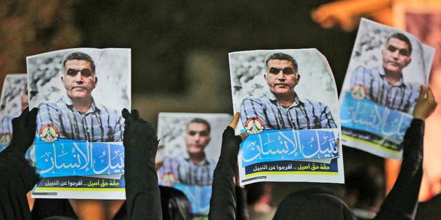 FILE- In this Thursday, May 14, 2015 file photo, Bahraini anti-government protesters hold up images of jailed human rights activist Nabeel Rajab during a solidarity protest outside his home in Bani Jamra, Bahrain. A jailed activist in Bahrain on trial for allegedly spreading "false news" is being investigated over a letter published in his name by French newspaper. Bahrain's Interior Ministry issued a statement early Thursday, Dec. 22, 2016,  announcing the new probe focusing on Nabeel Rajab over the article published by Le Monde on Tuesday. (AP Photo/Hasan Jamali, File)