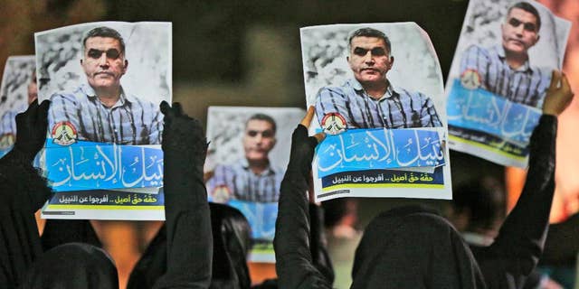FILE- In this Thursday, May 14, 2015 file photo, Bahraini anti-government protesters hold up images of jailed human rights activist Nabeel Rajab during a solidarity protest outside his home in Bani Jamra, Bahrain. A jailed activist in Bahrain on trial for allegedly spreading "false news" is being investigated over a letter published in his name by French newspaper. Bahrain's Interior Ministry issued a statement early Thursday, Dec. 22, 2016, announcing the new probe focusing on Nabeel Rajab over the article published by Le Monde on Tuesday. (AP Photo/Hasan Jamali, File)
