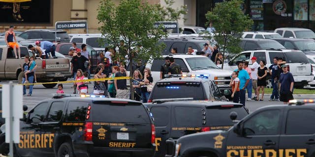 People at the Central Texas MarketPlace watch a crime scene near the parking lot of a Twin Peaks restaurant Sunday, May 17, 2015, in Waco, Texas. (Rod Aydelotte/Waco Tribune-Herald via AP)