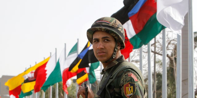 An Egyptian presidential guard soldier stands in front of flags of participating countries at the 12th summit of the Organization of Islamic Cooperation in Cairo, Egypt, Wednesday, Feb. 6, 2013.  The summit aims to address a wide range of issues including, Palestinian statehood, the Syrian crisis, poverty in the Islamic world and conflicts in Afghanistan and Somalia. (AP Photo/Amr Nabil)
