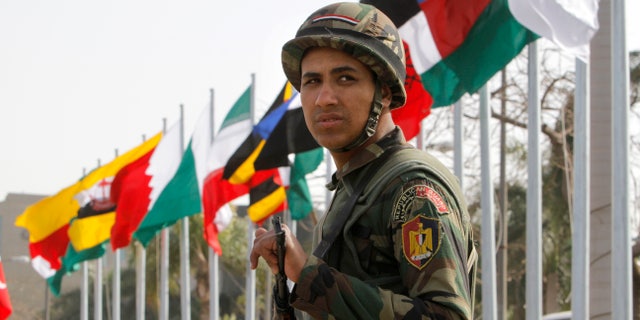 An Egyptian presidential guard soldier stands in front of flags of participating countries at the 12th summit of the Organization of Islamic Cooperation in Cairo, Egypt, Wednesday, Feb. 6, 2013. The summit aims to address a wide range of issues including, Palestinian statehood, the Syrian crisis, poverty in the Islamic world and conflicts in Afghanistan and Somalia. (AP Photo/Amr Nabil)