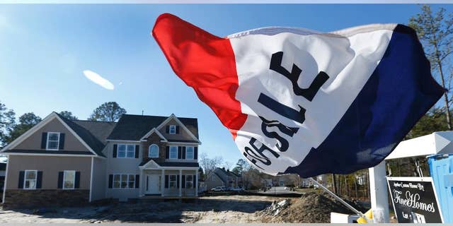 In this Thursday, Jan. 8, 2015 photo, a flag flaps in the breeze in front of a new home for sale in Richmond, Va. The Commerce Department reports on sales of new homes for December on Tuesday, Jan. 27, 2015. (AP Photo/Steve Helber)