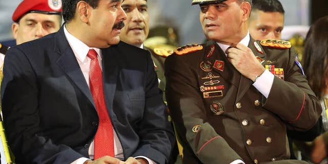 FILE - In this Oct. 27, 2014 file photo, Venezuela's President Nicolas Maduro, left, speaks with his Defense Minister Gen. Vladimir Padrino, during the new military chief's swearing-in ceremony at the Fort Tiuna military base in Caracas, Venezuela. Maduro on Monday, July 11, 2016 said he was creating a new government initiative to boost production and guarantee the smooth distribution of food supplies. He says that what is called the Great Mission of Sovereign Supplying will be headed Padrino, who will coordinate the work of every ministry. (AP Photo/Ariana Cubillos, File)