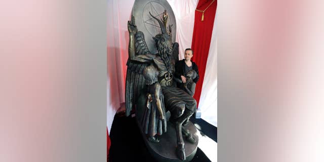 Lucien Greaves, in this Oct. 24, 2016, file photo, stands next to a statue of the goat-headed idol Baphomet at the headquarters of the Satanic Temple in Salem, Mass. Greaves said in 2016 the temple hopes to ensure Satanists "have a place in the world."