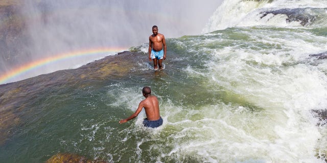 BXDT97 Man jumps into Devil's Pool at Victoria Falls.