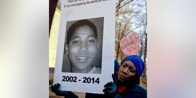 FILE - In this Dec. 1, 2014, file photo, Tomiko Shine holds up a picture of Tamir Rice, the 12 year old boy fatally shot by a rookie police officer in Cleveland, Ohio, on Nov. 22, during a protest in Washington, D.C. Cleveland.com reported newly public recorded police interviews with Officers Frank Garmback and Timothy Loehmann were done within days of the November 2014 death of Rice, who'd been playing with a pellet gun. (AP Photo/Jose Luis Magana, File)