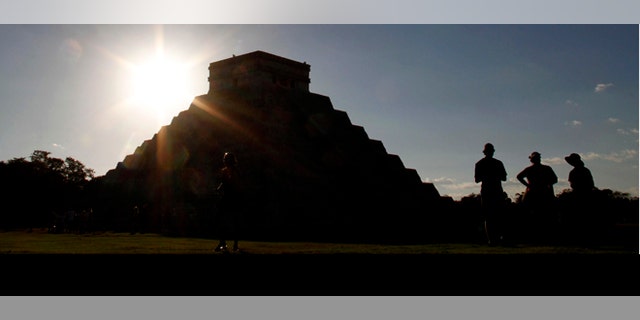 People gather in front of the Kukulkan Pyramid in Chichen Itza, Mexico, Thursday, Dec. 20, 2012. American seer Star Johnsen-Moser led a whooping, dancing, drum-beating ceremony Thursday in the heart of Mayan territory to consult several of the life-sized crystal skulls, which adherents claim were passed down by the ancient Maya. (AP Photo/Israel Leal)