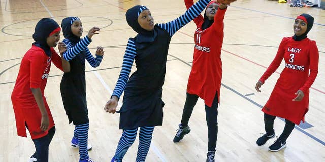 FILE - In this June 16, 2015, file photo, East African Muslim girls practice basketball in their new uniforms in Minneapolis. Members of basketball's international governing body are expected to vote to eliminate a rule that bans religious headgear during competition. The vote could come during a meeting on Thursday or Friday, May 5, 2017. Headgear was banned for safety reasons two decades ago out of fear it could fall off, causing a player to slip or become entangled. (AP Photo/Jim Mone, File)