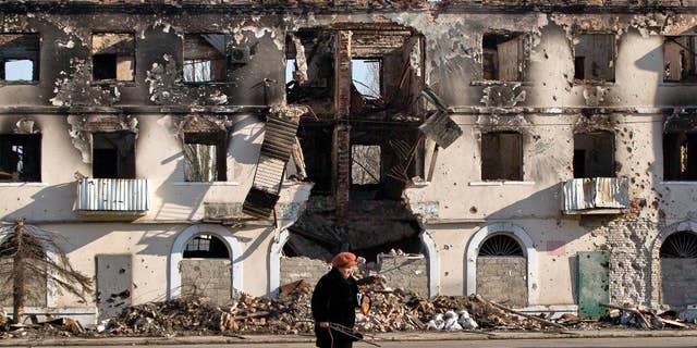 March 9, 2015: An elderly woman walks by a destroyed building in Vuhlehirsk, Ukraine.