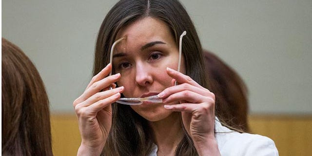 FILE - In this Feb. 18, 2015 file photo, Jodi Arias puts on her glasses during her sentencing retrial at Maricopa County Superior Court in Phoenix. The long-running legal saga of convicted murderer Arias draws to a close Monday, April 13 as a judge formally imposes a life sentence in the 2008 shooting and stabbing death of her on-again-off-again boyfriend. (Tom Tingle/Pool Photo via AP, File)