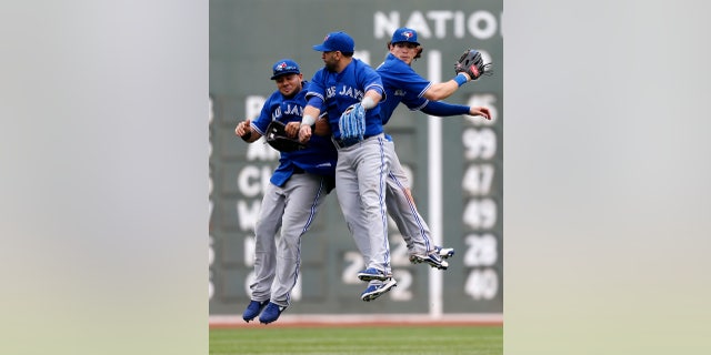Toronto Blue Jays', from left, Melky Cabrera, Jose Bautista and Colby Rasmus celebrate after defeating the Boston Red Sox 3-2 in a baseball game in Boston, Saturday, May 11, 2013. (AP Photo/Michael Dwyer)