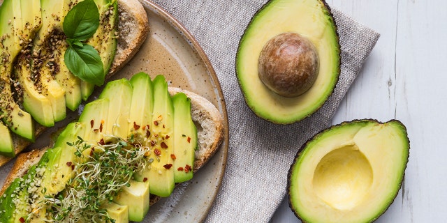 Toast with sliced avocado topping, basil leaf and seasoning.