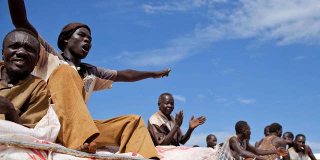 FILE - In this Sunday Sept. 16, 2012 file photo, South Sudanese men sing and clap as they ride on the truck carrying WFP food supplies to a warehouse, in Yida camp, South Sudan.  The World Food Program said Friday April 14, 2017 it is "horrified" to learn that three of its South Sudan workers were killed this week in violence in the western town of Wau, as the country's civil war continues under warnings of possible genocide. (AP Photo/Mackenzie Knowles-Coursin, File)