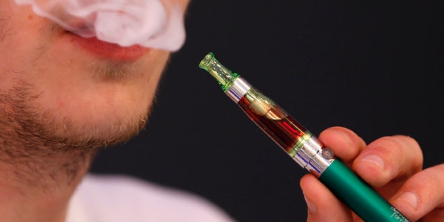 Martin Borne, co-founder of electronic cigarette retailer "Demain J'arrete", demonstrates the use of an electronic cigarette in his shop in Paris October 8, 2013. The European Parliament voted on Tuesday to water down proposed tobacco legislation, rejecting an immediate ban on menthol cigarettes and scaling down the size of health warnings on packets following intense lobbying by tobacco companies. The parliament also said manufacturers should be free to sell smokeless e-cigarettes, which deliver nicotine electronically and are a rapidly growing market, as a consumer product when not being marketed as an aide to help people quit smoking. REUTERS/Charles Platiau (FRANCE - Tags: SOCIETY HEALTH BUSINESS POLITICS) - RTX143QN