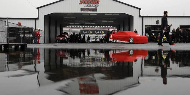 Crew members push the car of Kyle Larson in the garage area before the NASCAR Sprint Cup series auto race, Sunday, June 5, 2016, in Long Pond, Pa. (AP Photo/Matt Slocum)