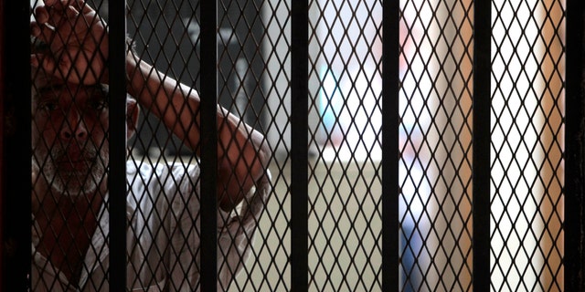 An inmate who survived a prison fire stands inside the medical attention area of the prison in Comayagua, Honduras, Honduras, early Thursday Feb. 16, 2012.  A fire started by an inmate tore through the prison Tuesday night, killing over 300 people, according to officials. (AP Photo/Esteban Felix)