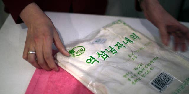 A saleswoman shows off a locally produced t-shirt and towel made out of hemp in Pyongyang. Hemp is, in fact, grown in North Korea with official sanction.