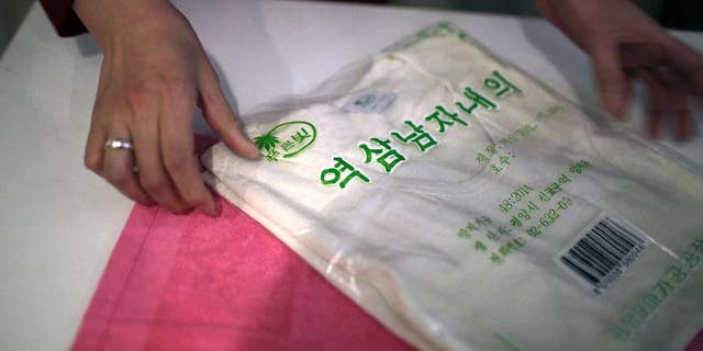 A saleswoman shows off a locally produced t-shirt and towel made out of hemp in Pyongyang. Hemp is, in fact, grown in North Korea with official sanction.