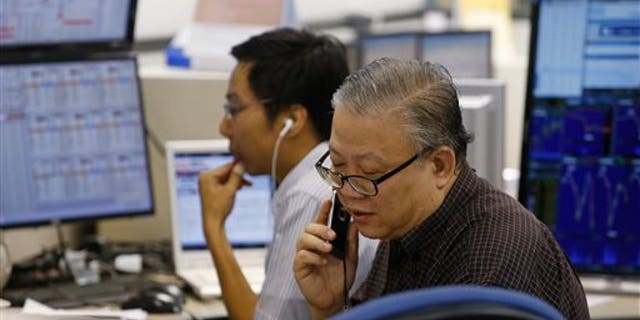 A broker talks on phone at a brokerage firm in Hong Kong, Wednesday, July 8, 2015.