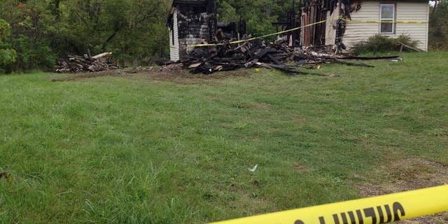 Police tape cordons off the remains of a house. Wednesday, Sept. 14, 2016, in rural Richland County, near Mansfield, Ohio, where authorities say a woman's body was found nearby. Police say a suspect in the abduction of a woman in neighboring Ashland on Tuesday confessed to killing a woman in the house in June, which was then destroyed in a fire. (AP Photo/Ann Sanner)