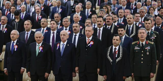 Turkey's President Recep Tayyip Erdogan, 4th left, accompanied by, from left to right, Kemal Kilicdaroglu, leader of the Republican People's Party (CHP), Prime Minister Binali Yildirim, Ismail Kahraman, Speaker of the Grand National Assembly of Turkey, Turkish Constitutional Court Chairman Zuhtu Arslan and Chief of the General Staff of the Turkish Armed Forces, Hulusi Akar, sing the national anthem as they attend a ceremony, part of the 55th anniversary of the founding of Turkey's Constitutional Court, in Ankara, Turkey, on Tuesday, April 25, 2017. Legislators representing Europe's top human rights body, the Strasbourg-France-based Parliamentary Assembly of the Council of Europe, on Tuesday voted in favour of re-opening monitoring procedures in Turkey in a move that reflects its strong concern over the functioning of democratic institutions in the country. (Press Presidency Press Service, Pool Photo via AP)