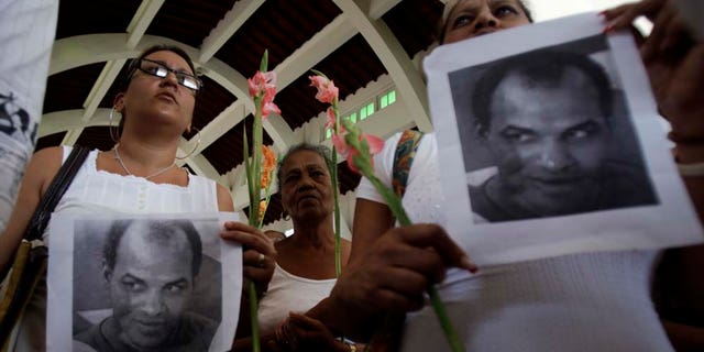 Members of Cuba's dissident group Ladies in White hold up photographs of the late political prisoner Orlando Zapata Tamayo during their weekly march in Havana, Cuba, Sunday, Feb. 6, 2011. Tamayo died on Feb. 23 following a lengthy hunger strike. Cuba freed Guido Sigler , a prominent political prisoner, on Friday and the Roman Catholic Church said Angel Moya, another political prisoner, would be released soon and allowed to stay in the country. (AP Photo/Javier Galeano)