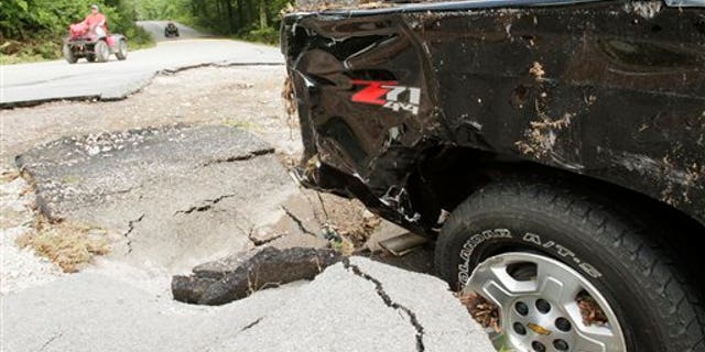 June 23: In this file photo sblah blah blagh earch and rescue workers ride all terrain vehicles past a truck that was damaged by flood waters at Albert Pike campground near Caddo Gap, Ark.