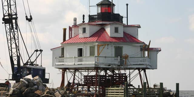 FILE - In this June 6, 2007 file photo, a barge works alongside the Thomas Point Shoal Lighthouse near Annapolis, Md., as part of a renovation project on the structure. Authorities are investigating a break-in and vandalism at the historic lighthouse in Maryland. Maryland Natural Resources Police say the lighthouse was targeted between April 15 and April 16, 2016. (AP Photo/Brian Witte)