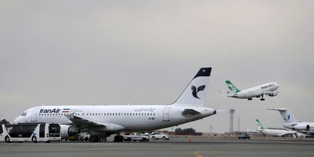 In this photo taken on Feb. 7, 2016, A Iranian Mahan Air passenger plane takes off as a plane of Iran's national air carrier, Iran Air, is parked at left, at Mehrabad airport in Tehran, Iran. Boeing Co. said Tuesday it signed an agreement with Iran Air "expressing the airline's intent" to buy its aircraft, setting up the biggest business deal between the Islamic Republic and America since the 1979 U.S. Embassy takeover in Tehran. (AP Photo/Vahid Salemi)