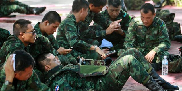 Thai soldiers rest on the ground at police headquarters after being deployed to prevent an anti-coup demonstration in Bangkok, Thailand Sunday, June 1, 2014. An anti-coup activist in Thailand called Friday for a weekend rally to defy the military government's ban on demonstrations, urging those opposed to the takeover to wear masks and be ready for cat-and-mouse chases with soldiers in the capital. (AP Photo/Wason Wanichakorn)