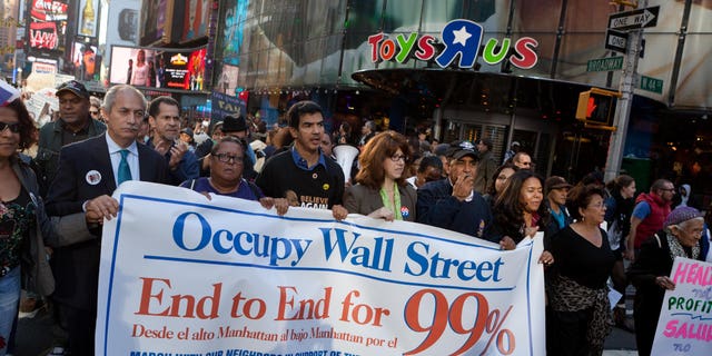 FILE – Demonstrators affiliated with the Occupy Wall Street protests walk through Times Square during an 11-mile march from uptown Manhattan to Zuccotti Park, Monday, Nov. 7, 2011, in New York. Elected officials, labor leaders and other protesters started walking in Washington Heights to show solidarity with the Occupy Wall Street movement. (AP Photo/John Minchillo)