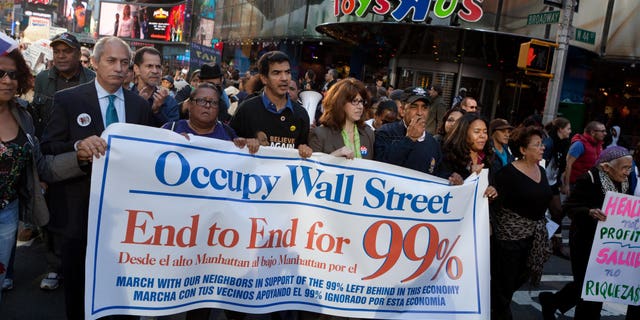 FILE – Demonstrators affiliated with the Occupy Wall Street protests walk through Times Square during an 11-mile march from uptown Manhattan to Zuccotti Park, Monday, Nov. 7, 2011, in New York. Elected officials, labor leaders and other protesters started walking in Washington Heights to show solidarity with the Occupy Wall Street movement. (AP Photo/John Minchillo)