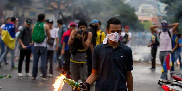 An opposition demonstrator prepares to throw a molotov cocktail at police after clashes broke out at a protest in Caracas, Venezuela, Thursday, Feb. 12, 2015. Venezuelans staged dueling marches to mark the anniversary of last year's bloody protest movement that resulted in more than 40 people being killed, including both government supporters and opponents. Dozens of protesters remain jailed, while the social issues they railed against last year- a faltering economy, widespread shortages and pervasive violent crime - have only gotten worse. (AP Photo/Fernando Llano)