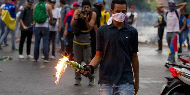 An opposition demonstrator prepares to throw a molotov cocktail at police after clashes broke out at a protest in Caracas, Venezuela, Thursday, Feb. 12, 2015. Venezuelans staged dueling marches to mark the anniversary of last year's bloody protest movement that resulted in more than 40 people being killed, including both government supporters and opponents. Dozens of protesters remain jailed, while the social issues they railed against last year- a faltering economy, widespread shortages and pervasive violent crime - have only gotten worse. (AP Photo/Fernando Llano)