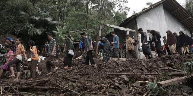 Villagers walk through an area wrecked by landslides in Banjarnegara, Central Java, Indonesia.