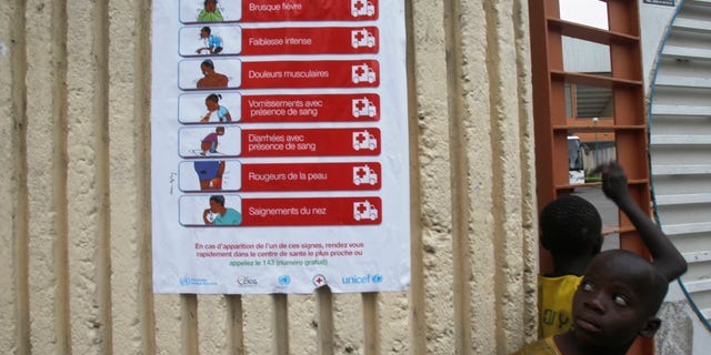 Boys stand next to a poster, pertaining to the Ebola virus, during a training session by Sierra Leone's national soccer team at the Felix Houphouet Boigny stadium in Abidjan, September 5, 2014. Ivory Coast will host their African Nations Cup qualifier against Ebola-affected Sierra Leone this weekend following a special meeting of the country?s national security council. The decision, announced in a government statement published in local media on Tuesday, comes one week after the government said it would not allow the match to go ahead, citing concerns over a possible Ebola outbreak. REUTERS/Luc Gnago (IVORY COAST - Tags: SPORT SOCCER HEALTH) - RTR4552S