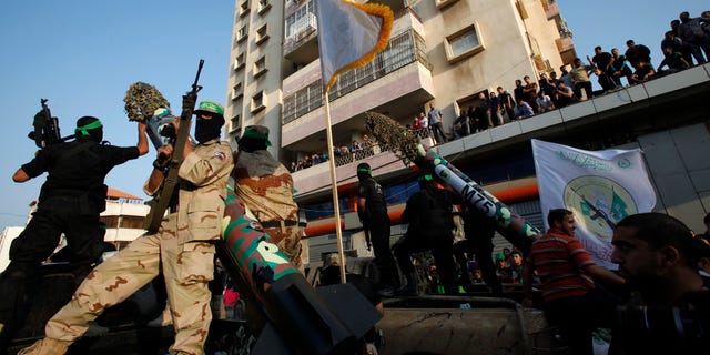 Masked Palestinian members of the Ezz Al-Din Al Qassam brigade, the military wing of Hamas, stand behind mock rockets on trucks during a parade to mark the anniversary of a battle against Israel in Gaza City.