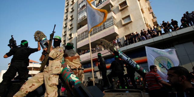Masked Palestinian members of the Ezz Al-Din Al Qassam brigade, the military wing of Hamas, stand behind mock rockets on trucks during a parade to mark the anniversary of a battle against Israel in Gaza City.