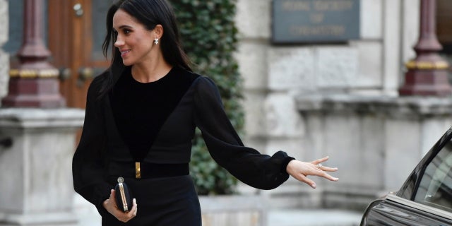 Meghan Markle closes her own car door while at her first royal solo outing.