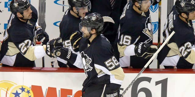 Pittsburgh Penguins Kris Letang (58) is greeted by teammates on the bench after scoring in the first period of an NHL hockey game against the Carolina Hurricanes, Friday, Nov. 28, 2014, in Pittsburgh. (AP Photo/Keith Srakocic)
