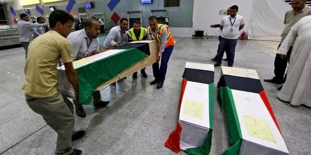 In this Saturday, June 27, 2015 photo, men arrange coffins draped with Kuwaiti flags belonging to a victim of a suicide bombing that targeted a Shiite mosque in Kuwait on Friday, as they arrive to Najaf Airport, for the funeral procession, in the Shiite holy city of Najaf, Iraq. Kuwaiti authorities on Sunday identified the suicide bomber behind an attack on a Shiite mosque that killed more than two dozens as a Saudi citizen who flew into the Gulf nation just hours before he blew himself up. (AP Photo/ Jaber al-Helo)