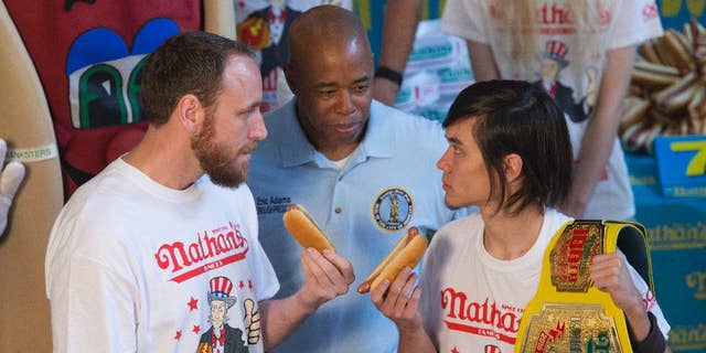Matt Stonie, right, reigning hot dog-eating champion, stares down eight-time champion Joey Chestnut during the official weigh-in for Nathans Famous hot dog eating contest, Friday, July 1, 2016, in New York. Brooklyn Borough President Eric Adams stands between the men. (AP Photo/Mary Altaffer)
