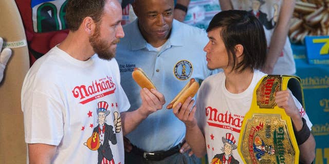 Matt Stonie, right, reigning hot dog-eating champion, stares down eight-time champion Joey Chestnut during the official weigh-in for Nathans Famous hot dog eating contest, Friday, July 1, 2016, in New York. Brooklyn Borough President Eric Adams stands between the men. (AP Photo/Mary Altaffer)